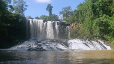  etkileyici şelale tropikal ağaçların altında tarafından çevreleyen açık mavi gökyüzü.