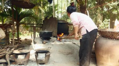 Kadın taşlarla yapılmış açık odun yanan ateş çukuru tencere pişirme altında orman ekleme