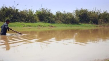 fisher nerede istiridye yakalanırlar göl kumlu alt üzerinde sürüklemek için bir itme sepeti kullanarak. Üçgen hasır sepet iki parçaya bölünmüş bir bambu direk bağlı olduğu. 