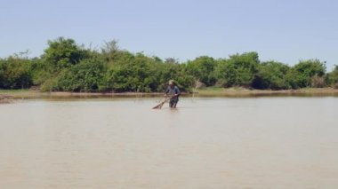 fisher nerede istiridye yakalanırlar göl kumlu alt üzerinde sürüklemek için bir itme sepeti kullanarak. Üçgen hasır sepet iki parçaya bölünmüş bir bambu direk bağlı olduğu. 