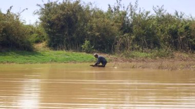 Fisher sallayarak ve kum, itme sepetten kaldırmak ve tekrar nerede istiridye yakalanırlar göl kumlu alt üzerinde sürükleme. 