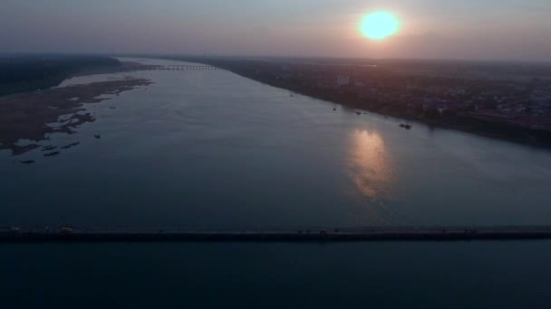 車やバイクの夕暮れ時 川に架かる竹橋を渡るの空中ショット 町を背景として — ストック動画