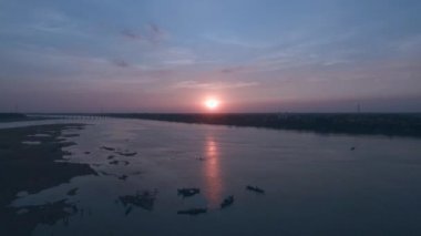 Hava: sinek geri bir bambu köprü Nehri üzerinde günbatımında çevresinde Yüzme insan siluetleri ile açığa demirlemiş tekneler