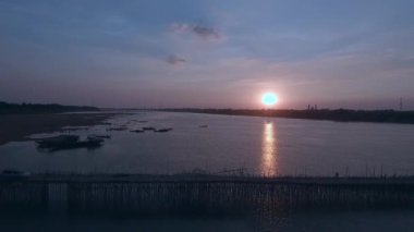 Araba ve günbatımında bir nehir üzerinde bir bambu köprüyü geçtikten hava kaydırma vurdu. Fon olarak şehir