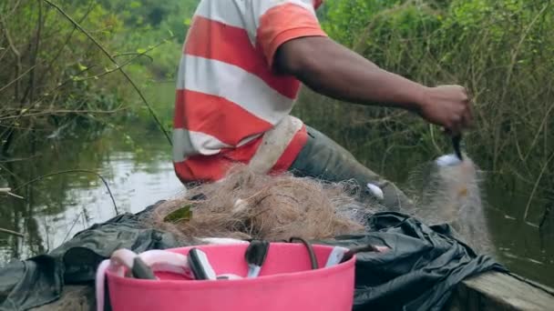 渔民在他的独木舟船头将水蛇从网里脱下来 放在一个塑料篮子里 — 图库视频影像