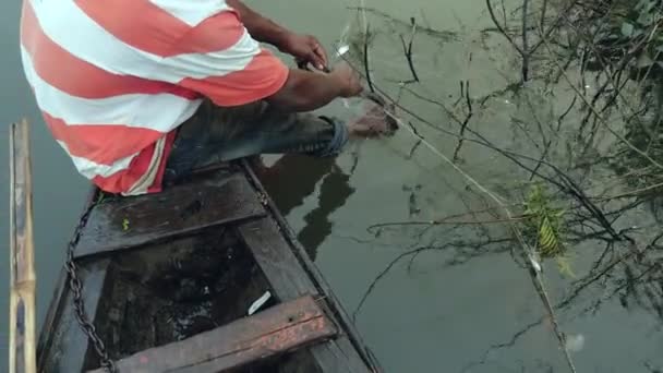 渔民在他的独木舟船头将水蛇从网里脱下来 放在一个塑料篮子里 — 图库视频影像