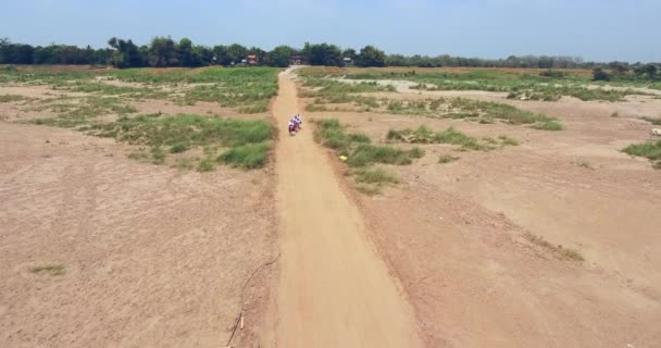 カンポン カンボジア 2019 ショット空中ドローン ドライ フィールドの未舗装の道路上のバイクに乗って 人の若い生徒 — ストック動画