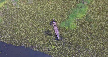 Kanosunun pruvasında oturan ve havuzda yengeç arayan bir kadının uzaktan kumandalı görüntüsü.