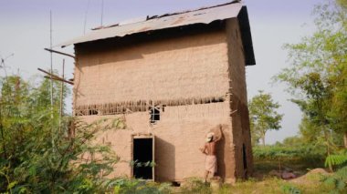 Yeni bir amaç için tütün ambarının tüm yüzeyini çamurla kaplayan bir adam. (Yenilenmiş tütün ahırı )