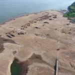Overhead drone of straw huts and wooden bungalows spread over sand beach