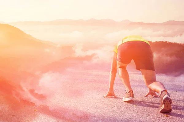 Athlete man in running start pose to mountain.