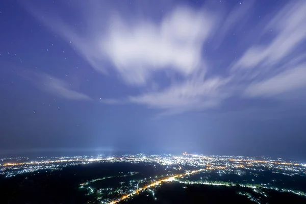 Las luces de la ciudad por la noche con cielos azules y estrellas . — Foto de Stock