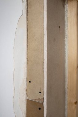 Siyah metal vidalarla tutturulmuş alçıpan parçaları, kapı kenarı tamiri