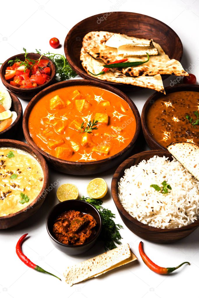 Assorted indian food for lunch or dinner, rice, lentils, paneer, dal makhani, naan, chutney, spices over moody background. selective focus