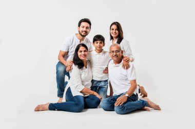 Beyaz arka planda soyutlanmış Hintli bir aile, beyaz bluz ve kot pantolon giyen yaşlı ve genç bir çift. seçici odak