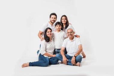 Beyaz arka planda soyutlanmış Hintli bir aile, beyaz bluz ve kot pantolon giyen yaşlı ve genç bir çift. seçici odak
