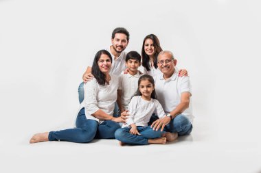 Beyaz arka planda oturan Hintli aile. Beyaz bluz ve kot pantolon giyen son sınıf ve genç bir çift. seçici odak