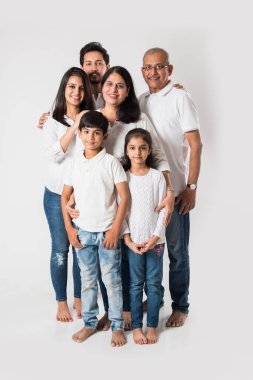 Beyaz arka planda soyutlanmış Hintli bir aile, beyaz bluz ve kot pantolon giyen yaşlı ve genç bir çift. seçici odak