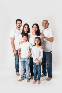 Beyaz arka planda soyutlanmış Hintli bir aile, beyaz bluz ve kot pantolon giyen yaşlı ve genç bir çift. seçici odak