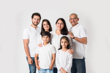 Beyaz arka planda soyutlanmış Hintli bir aile, beyaz bluz ve kot pantolon giyen yaşlı ve genç bir çift. seçici odak