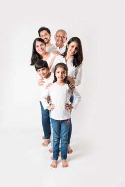 Beyaz arka planda soyutlanmış Hintli bir aile, beyaz bluz ve kot pantolon giyen yaşlı ve genç bir çift. seçici odak