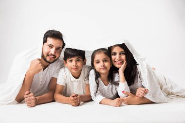 Çocuklu Hintli aileler yatak örtüsünün altında yatıyor.