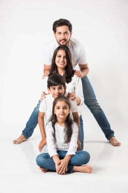 4 kişilik mutlu Hint ailesi beyaz arka planda izole edilmiş. Beyaz bluzlu ve kot pantolonlu çocukları olan genç bir çift. seçici odak