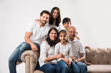 Mutlu Hintli aile beyaz arka planda koltukta ya da kanepede oturuyor.