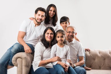 Mutlu Hintli aile beyaz arka planda koltukta ya da kanepede oturuyor.