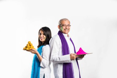 Baba ve kızı Holi oynuyorlar, ellerinde laddu ve renklerle dolu bir tabak tutuyorlar. beyaz arkaplan üzerinde izole
