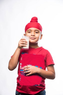 Indian Sikh/punjabi small boy holding a glass full of milk, isolated over white background clipart