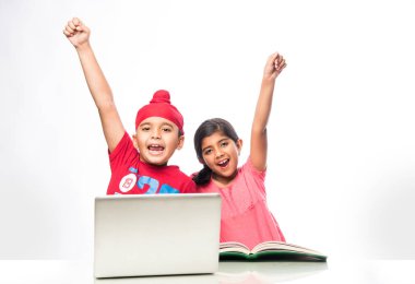 Hint Sih/Punjabi çocuk ve kitap ve dizüstü bilgisayar çalışma masasında ile okuyan kız