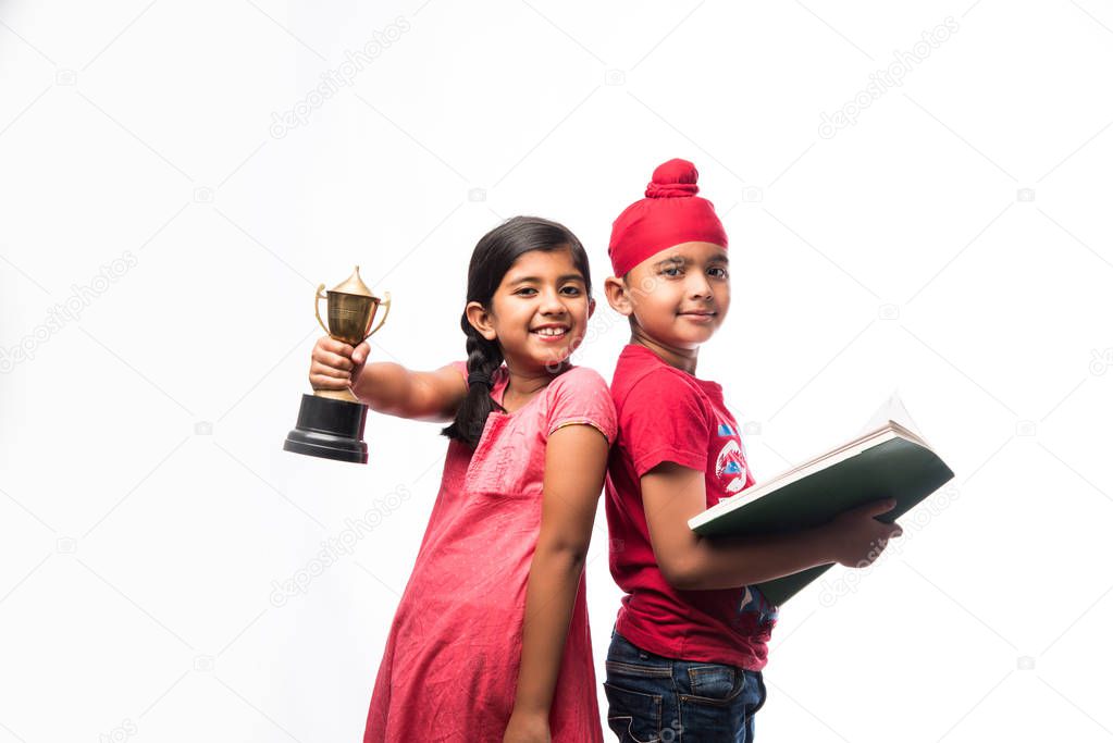 Indian  sikh / punjabi small girl and boy standing with a book and Victory Cup - education and success concept 