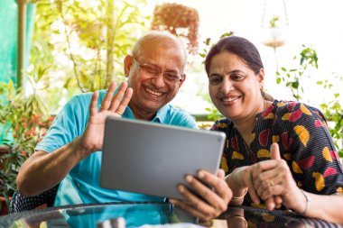 Hint/Asya kıdemli çift görüntülü kanepe veya evde, bahçede seçici odak otururken tablet/bilgisayarda sohbet