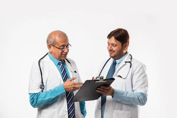 两名印度男医生站在白种人的背景上 用图表讨论医疗病例 — 图库照片