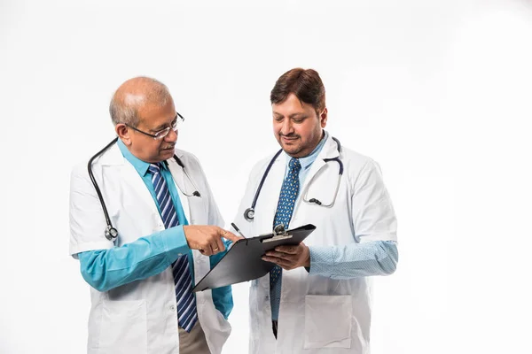 Two Indian Male Doctors Discussing Medical Case Chart Standing Isolated Stock Photo