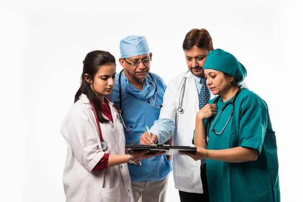 Four Indian doctors discussing on medical report while standing isolated over white background