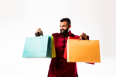 Kırmızı geleneksel giyim giyerken Hint Genç adam alışveriş, beyaz arka plan üzerinde izole ayakta