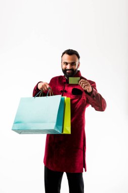 Kırmızı geleneksel giyim alışveriş yaparken Kart gösteren Hintli adam, beyaz arka plan üzerinde renkli kağıt torbalar ile izole ayakta