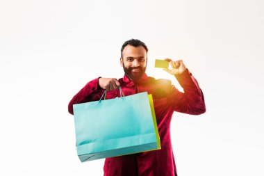 Kırmızı geleneksel giyim alışveriş yaparken Kart gösteren Hintli adam, beyaz arka plan üzerinde renkli kağıt torbalar ile izole ayakta