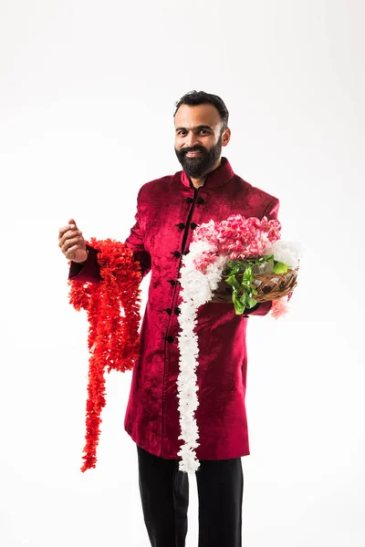 伝統的な布を身に着けている間 ディワリ 結婚式やお祭りに飾るための花輪 シリーズを保持するインドの男 シャーワニ 白い背景の上に孤立して立って — ストック写真