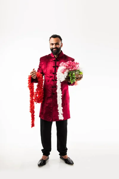 伝統的な布を身に着けている間 ディワリ 結婚式やお祭りに飾るための花輪 シリーズを保持するインドの男 シャーワニ 白い背景の上に孤立して立って — ストック写真