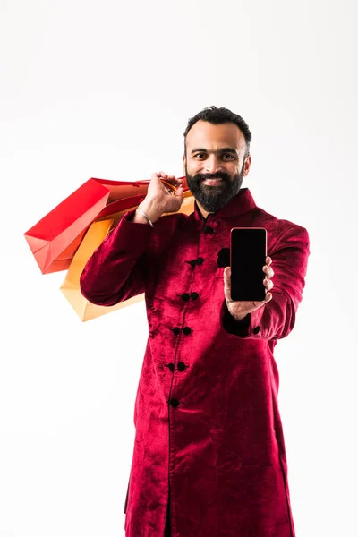買い物袋を持ちながらモバイル スマートフォンを使用するインド人男性 — ストック写真