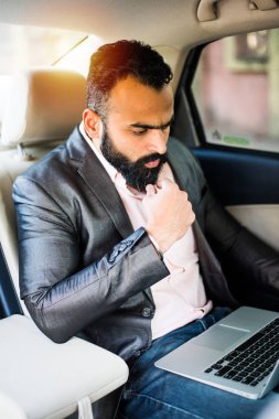 Araba içinde dizüstü bilgisayar ve telefon kullanarak Hint / asyalı genç işadamı, seçici odak