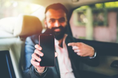 Araba içinde akıllı telefon kullanan Hint / asyalı genç işadamı, seçici odak