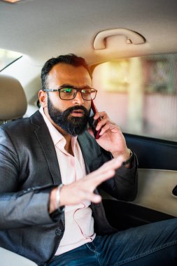 Araba içinde akıllı telefon kullanan Hint / asyalı genç işadamı, seçici odak