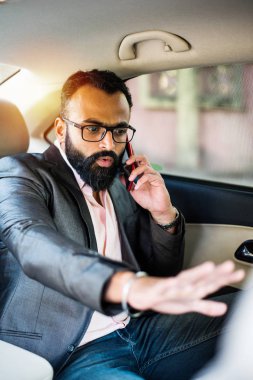 Araba içinde akıllı telefon kullanan Hint / asyalı genç işadamı, seçici odak