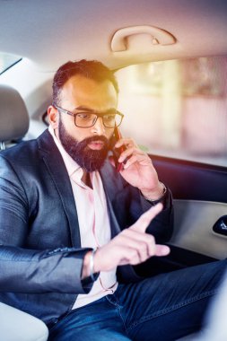 Araba içinde akıllı telefon kullanan Hint / asyalı genç işadamı, seçici odak