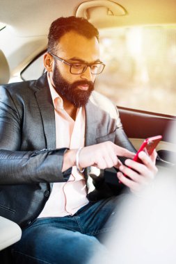 Araba içinde akıllı telefon kullanan Hint / asyalı genç işadamı, seçici odak