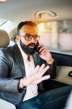 Araba içinde akıllı telefon kullanan Hint / asyalı genç işadamı, seçici odak